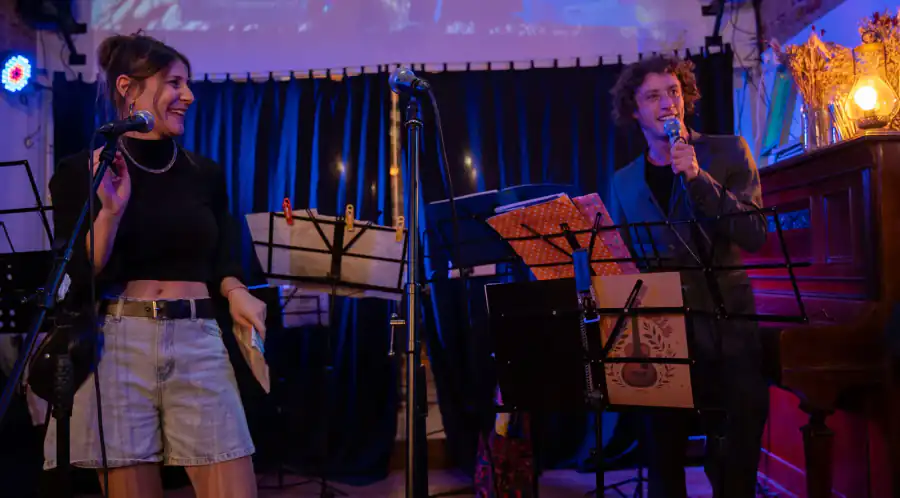 Dos artistas con micrófonos y atriles durante una presentación